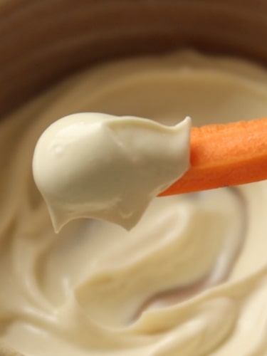 Bâtonnet de carotte trempé dans de la mayonnaise vegan