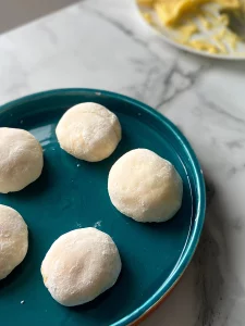 5 mochis au citron dans une assiette bleue, à l'arrière plan se trouve une assiette remplie de crème de citron jaune